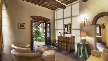 A cozy room with a wooden ceiling, a large mirror, a lamp, and comfortable seating.