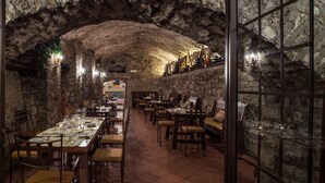 A restaurant with stone walls and a high ceiling, featuring tables set for dining. - Castello di Spaltenna- Small Luxury Hotels of the World (Gaiole in Chianti)