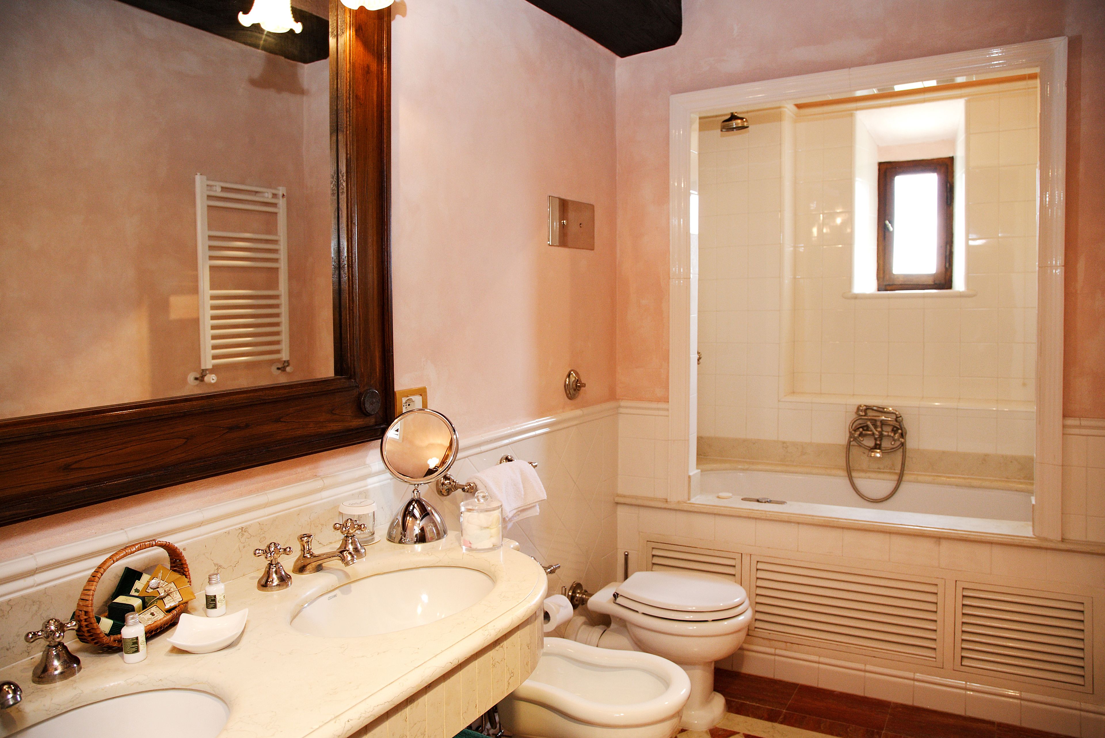 Een badkamer met een dubbele wastafel, toilet en bad.