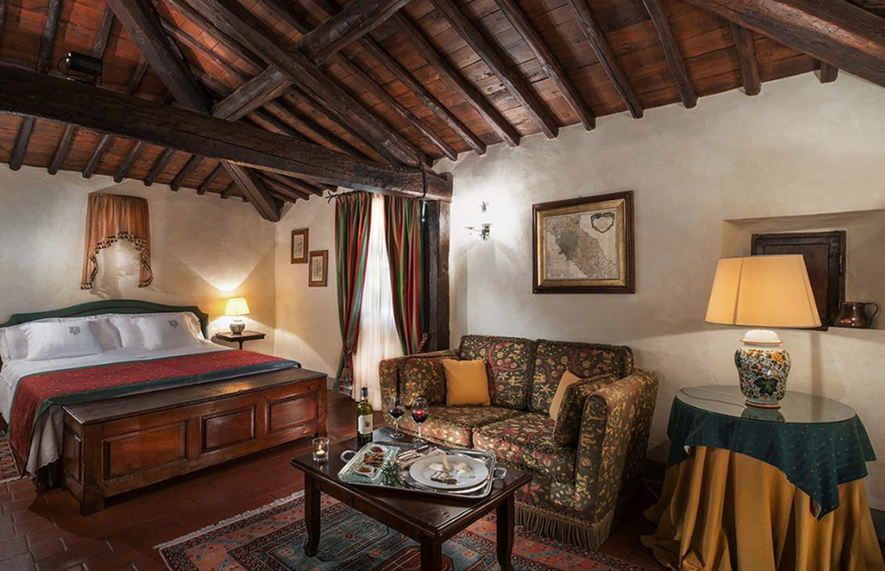 A room with a wooden bed, a sofa, a small table with a lamp, and a framed picture on the wall.