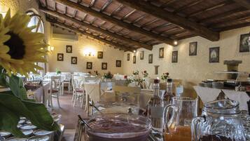 A dining area with tables and chairs, a buffet with food containers, and a coffee station with pitchers and cups.