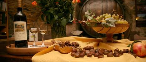 Una mesa con una botella de vino, copas, un cuenco de uvas y una granada.