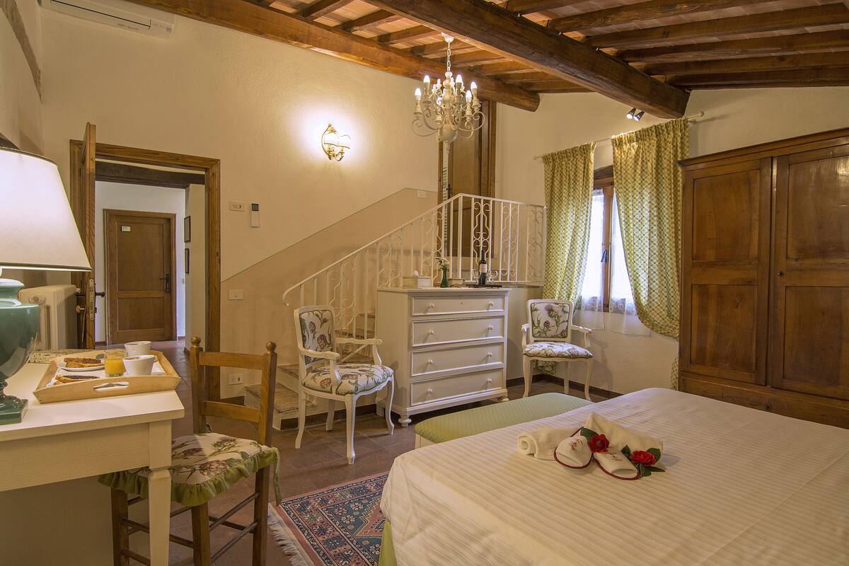 Un dormitorio con cama, cómoda, sillas y una escalera.