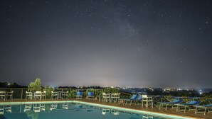 Ein Poolbereich mit Liegestühlen und Blick auf den Nachthimmel.