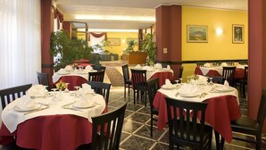 A restaurant with round tables set for dining, featuring a red tablecloth and white napkins. - Hotel Florida (Montecatini Terme)