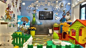 A children's playroom with colorful toys, a mural, and a television on the wall. - Hotel Florida (Montecatini Terme)
