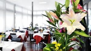 A dining area with tables set for service, a large white flower centerpiece, and a modern interior design. - Hotel Florida (Montecatini Terme)