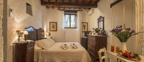 A bedroom with a wooden ceiling, a bed with white linens, a dresser, a mirror, and a window with curtains.