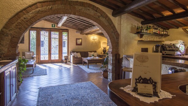 A spacious lobby with a stone archway, wooden ceiling beams, a bar area with a wine rack, and a reception desk. - Hotel Colle Etrusco Salivolpi (Castellina in Chianti)