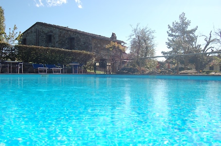Una piscina al aire libre, sombrillas, sillones reclinables de piscina