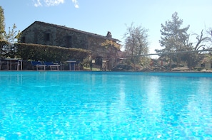 Een buitenzwembad, parasols bij het zwembad en ligstoelen