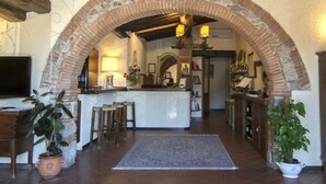 A rustic interior with a brick archway, wooden beams, a bar area, and potted plants. - Hotel Colle Etrusco Salivolpi (Castellina in Chianti)