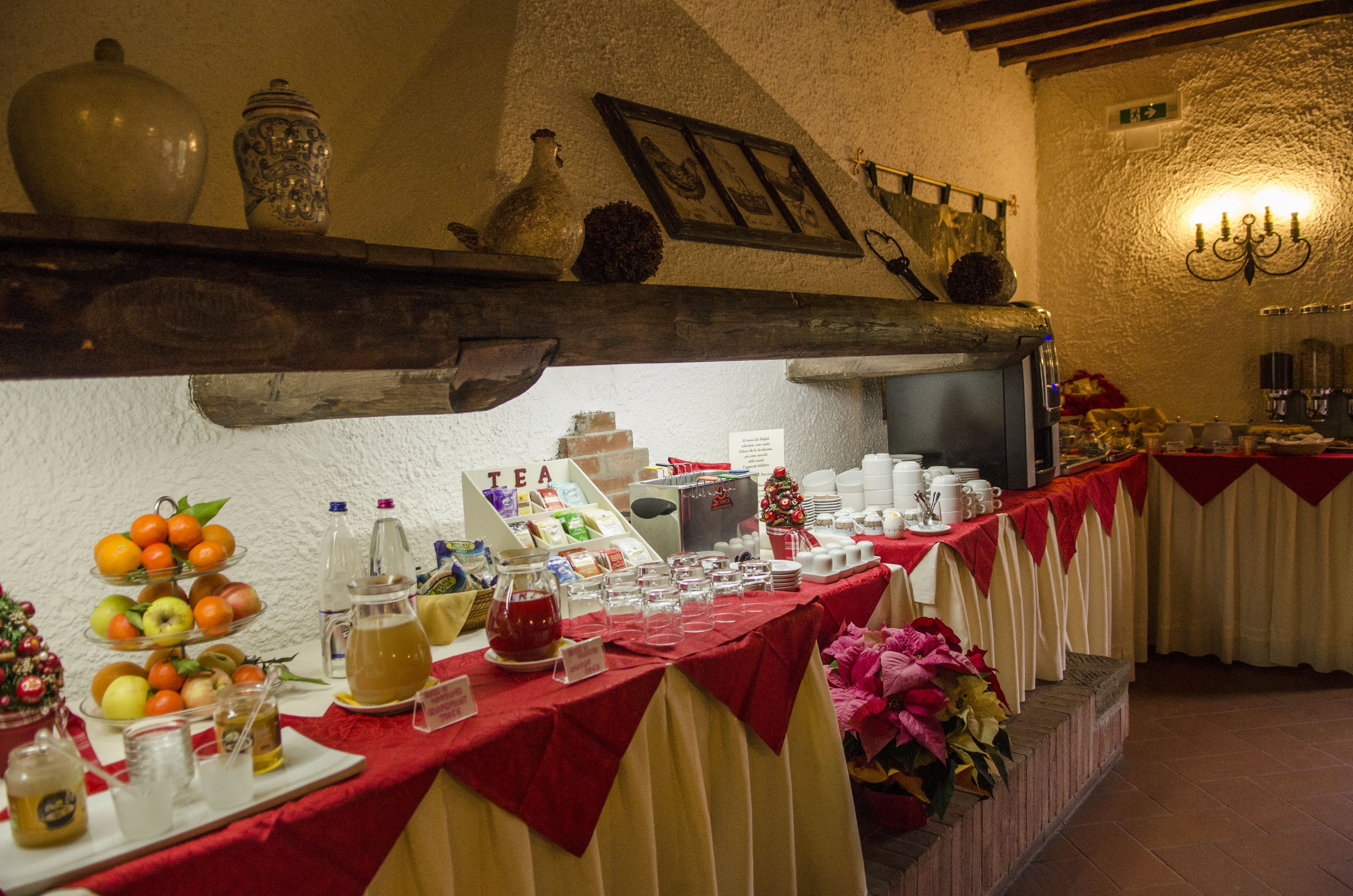 A buffet setup with a variety of food and drink options, including fruits, tea, and condiments.