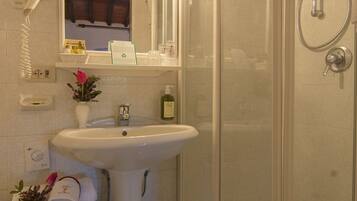 A bathroom with a glass-enclosed shower, a pedestal sink, and a vanity with a mirror.