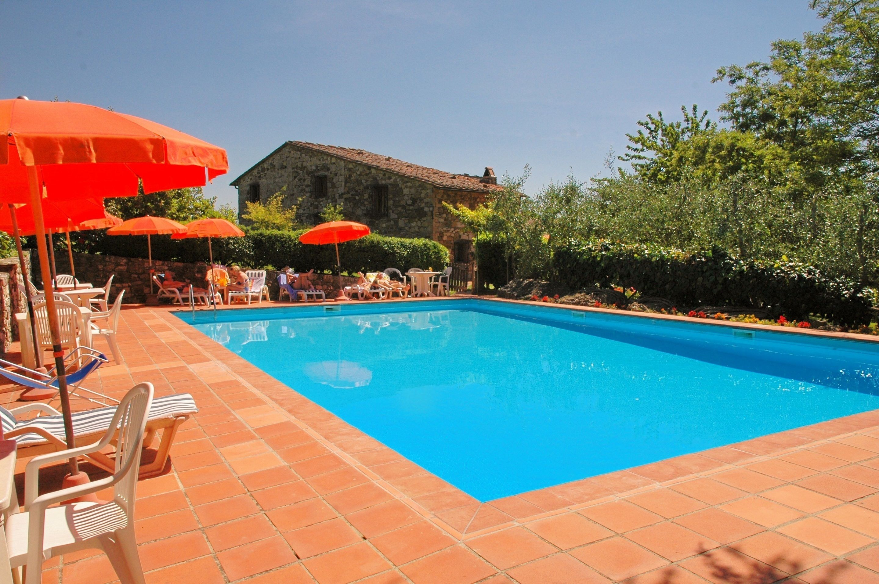 Una piscina al aire libre, sombrillas, sillones reclinables de piscina
