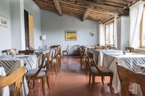 Un espace repas avec des tables et des chaises en bois, un sol carrelé et un plafond en bois rustique.
