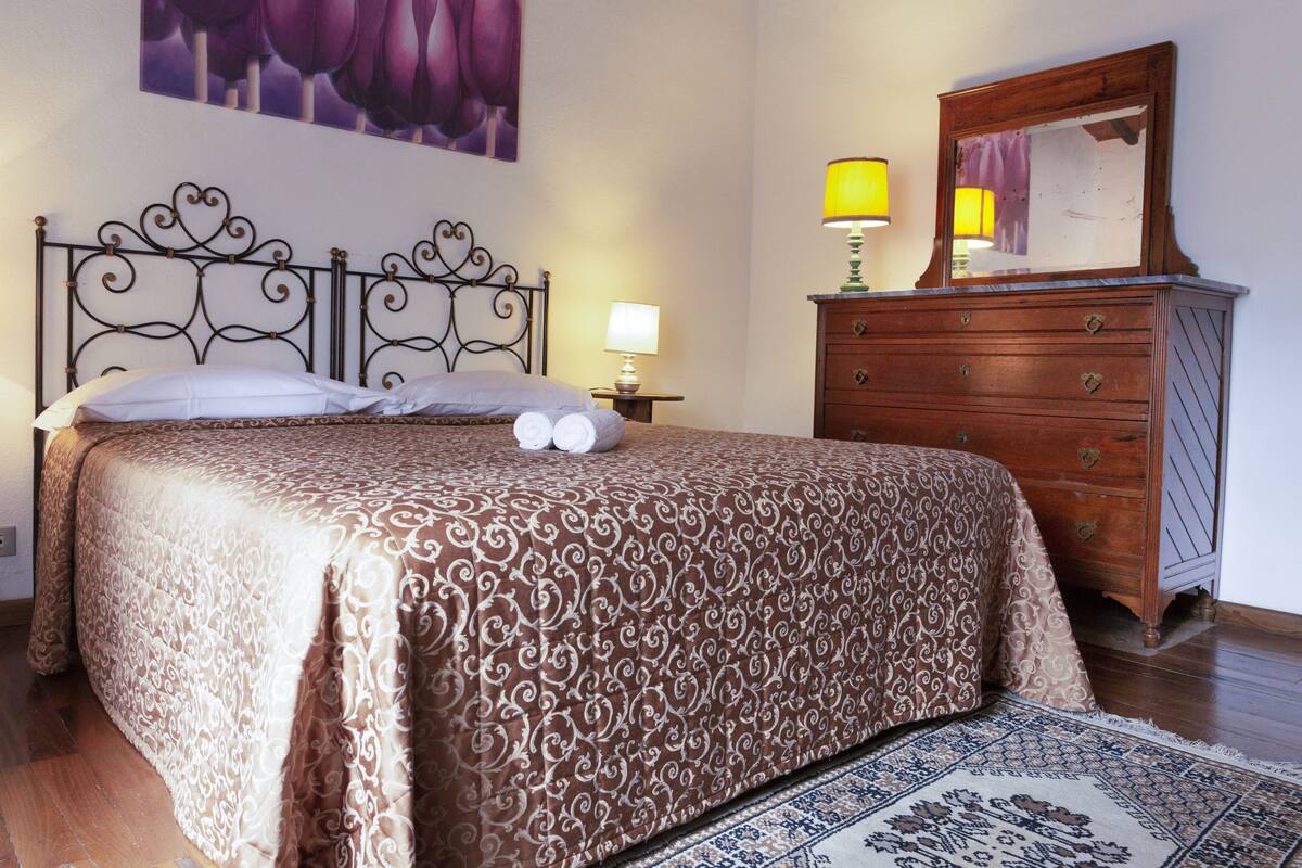 Un dormitorio con cama, cómoda, lámpara y alfombra.