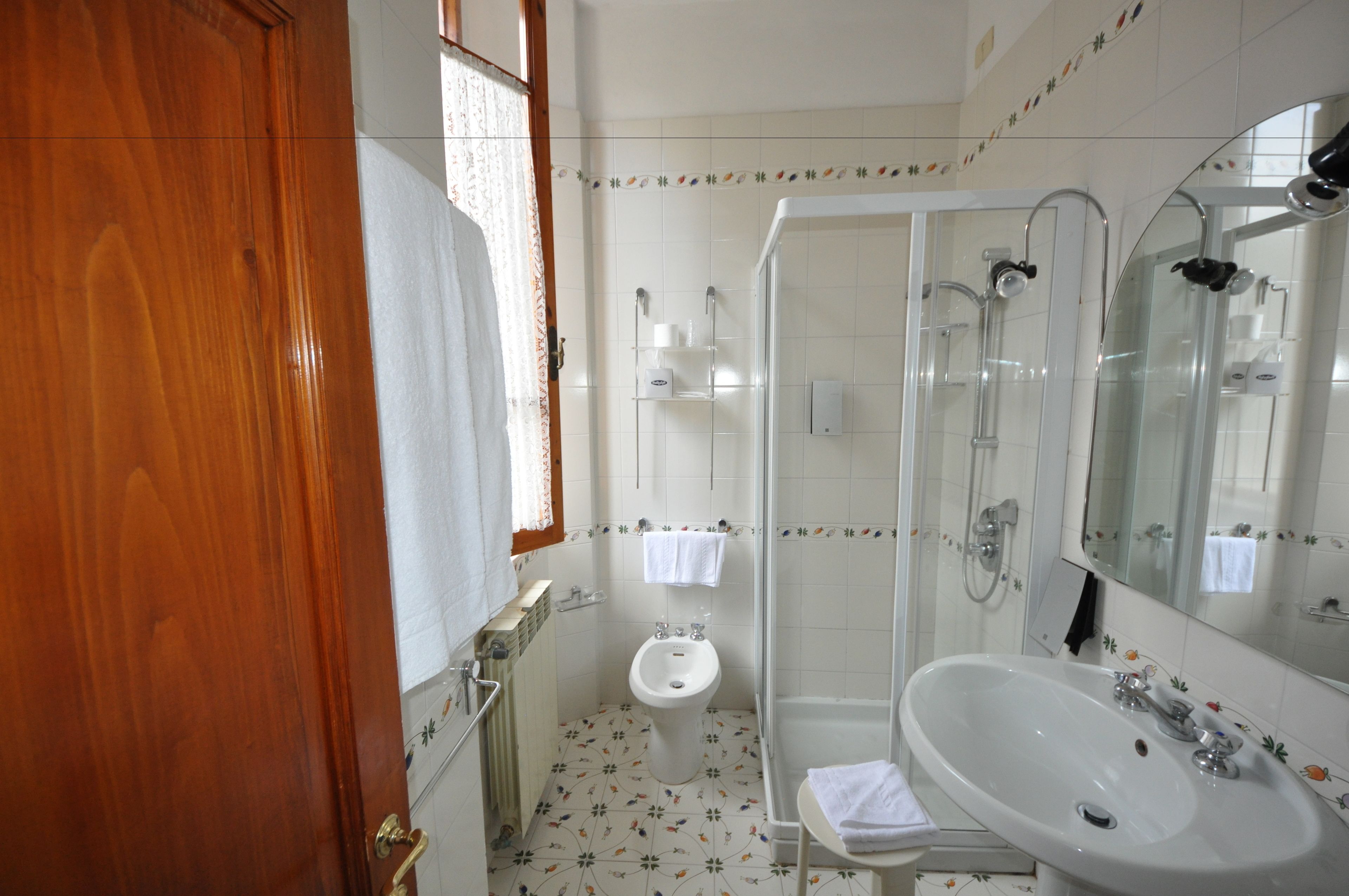 Un baño con puerta de madera, un bidé, cabina de ducha y lavabo con espejo.