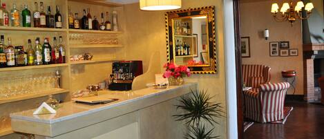A bar area with shelves of liquor bottles, a coffee machine, and a mirror with a decorative frame.