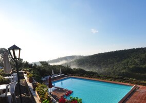 Una piscina al aire libre, sombrillas, sillones reclinables de piscina