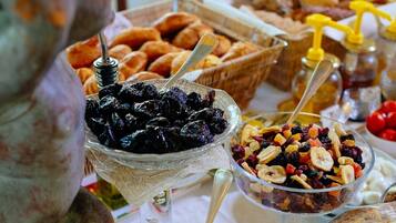 Une table de buffet proposant une variété d’aliments, notamment des fruits, des noix et des pâtisseries.