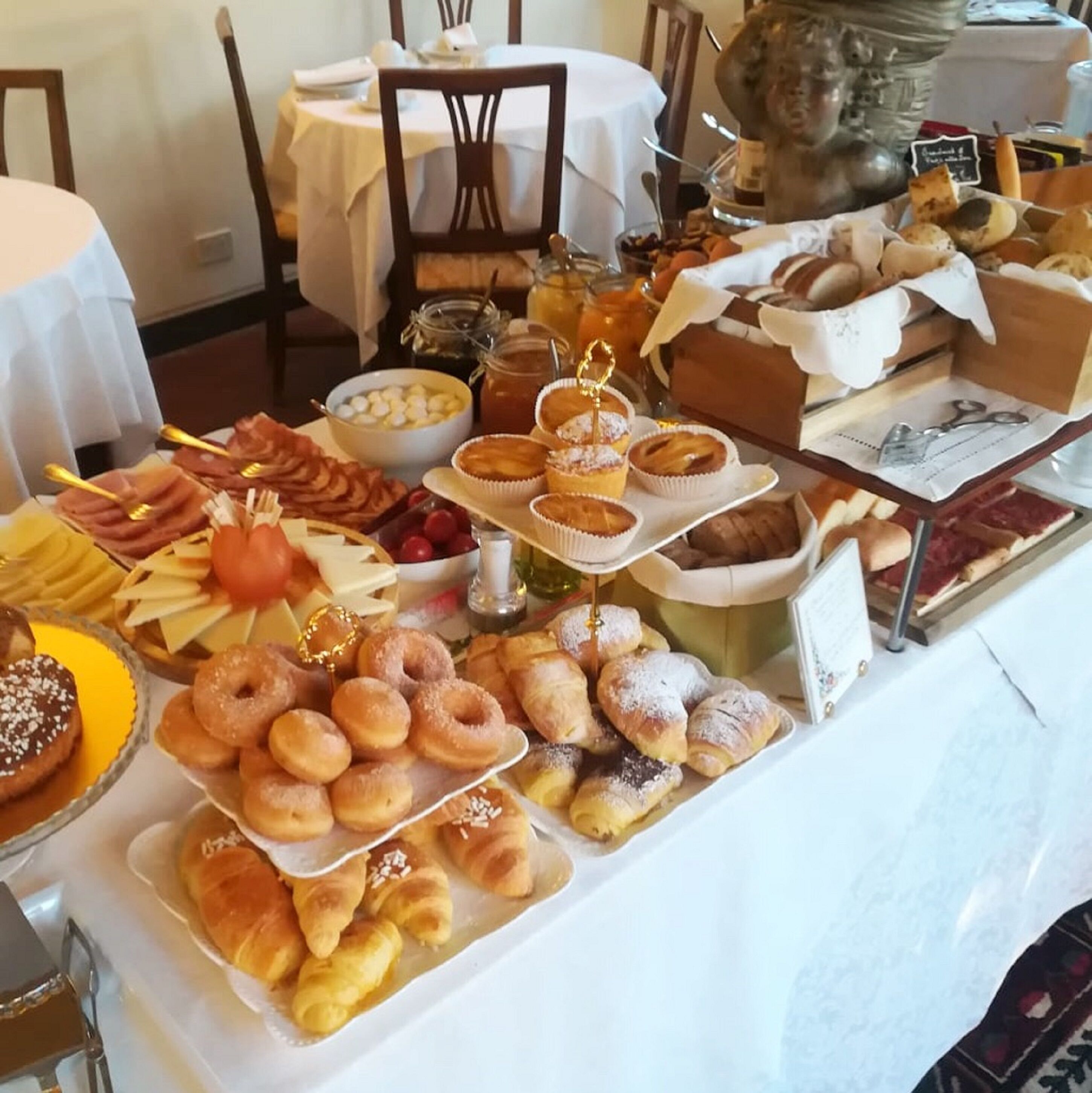 Un bufé con diversas opciones de pastelería, como cruasanes y donas, además de frutas y quesos.