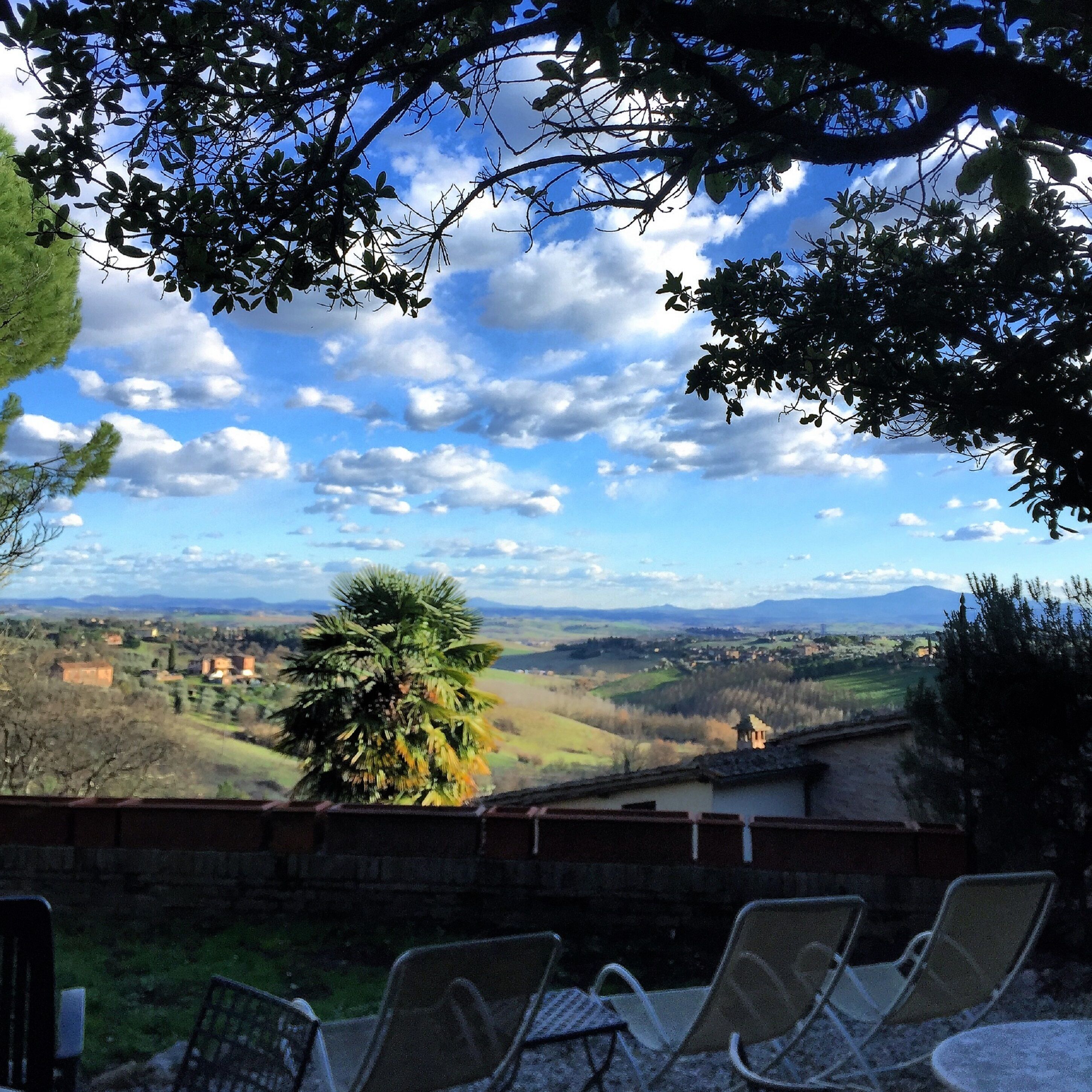 Une terrasse avec des sièges extérieurs et une vue sur une vallée, avec des maisons et des montagnes.