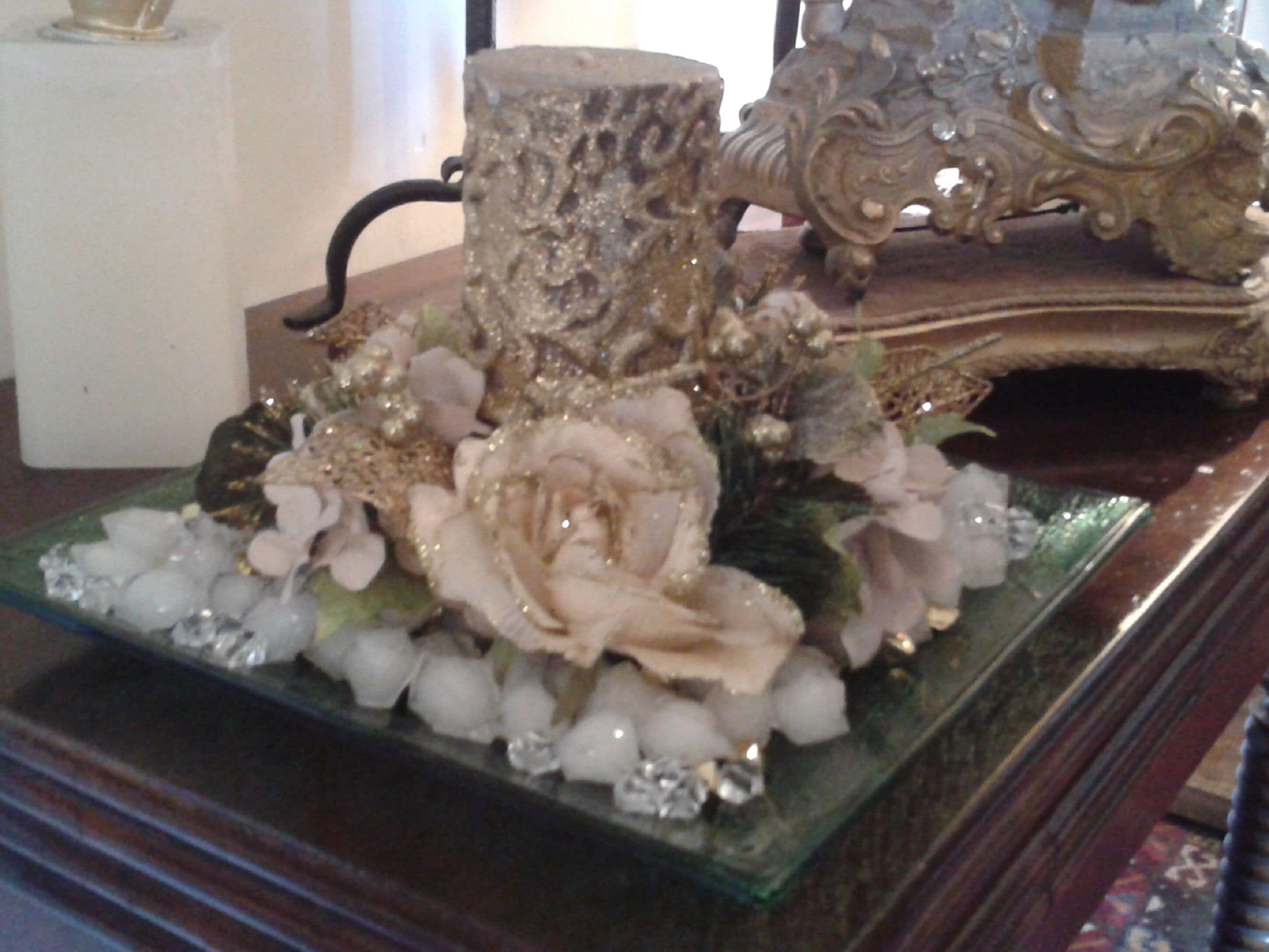 Un tavolo di vetro decorativo con un'elegante composizione floreale, una candela e un libro finemente decorato.