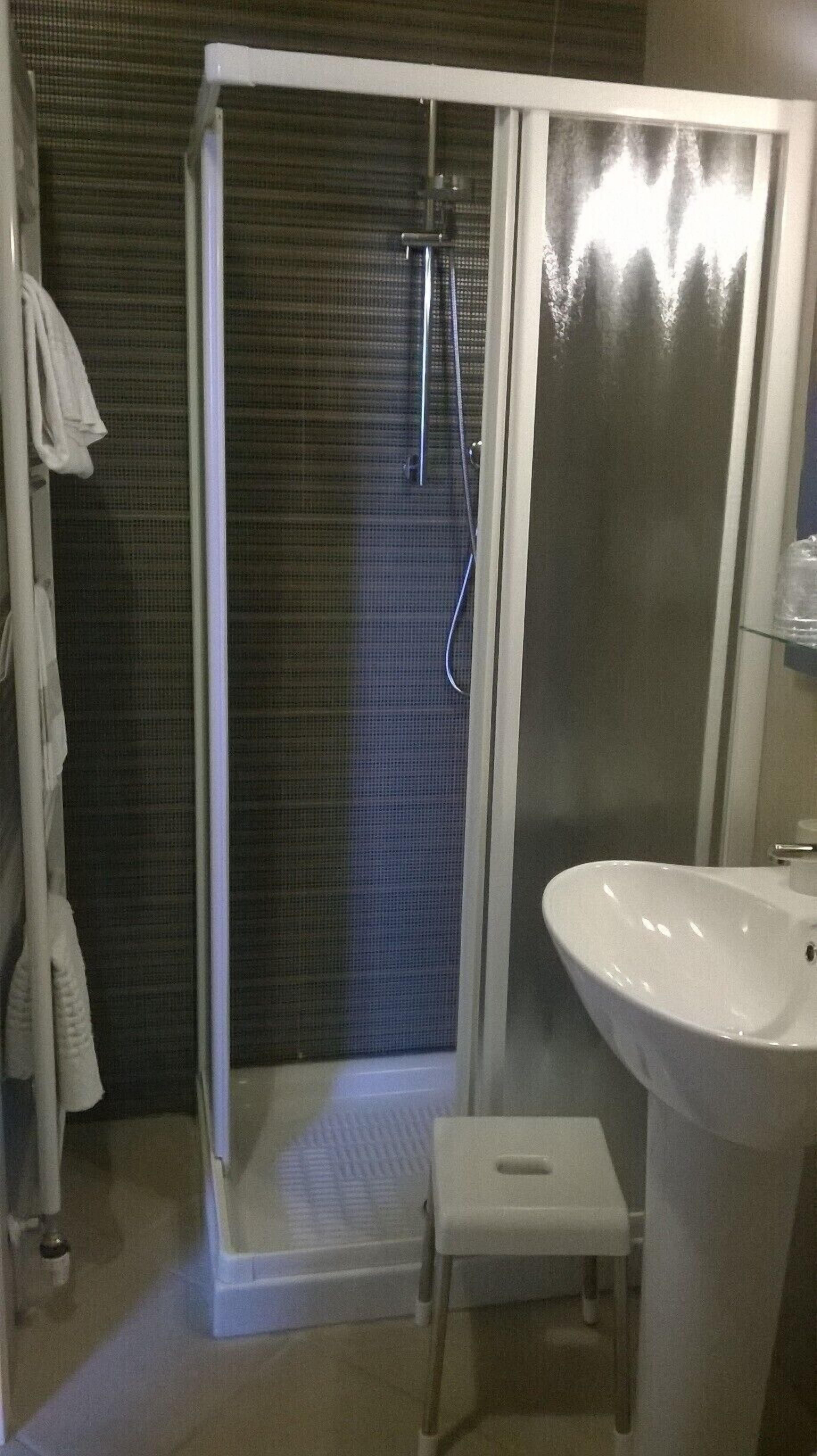 A bathroom with a walk-in shower, a sink, and a towel rack.