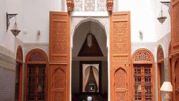 An interior with ornate wooden doors, a central archway, and a chandelier. - Riad au 20 Jasmins (Fes)