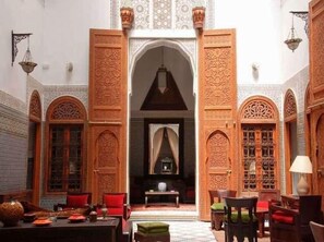 Un interior con puertas de madera ornamentadas, un arco central y una araña.
