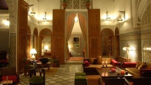 A traditional Moroccan interior with ornate arches, a central doorway, and a cozy seating area with cushions and a table. - Riad au 20 Jasmins (Fes)