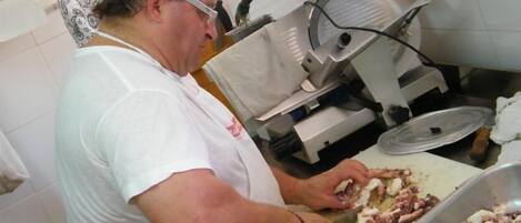 Una persona preparando comida en una cocina con una tabla de cortar grande, un fregadero y un bol de metal.
