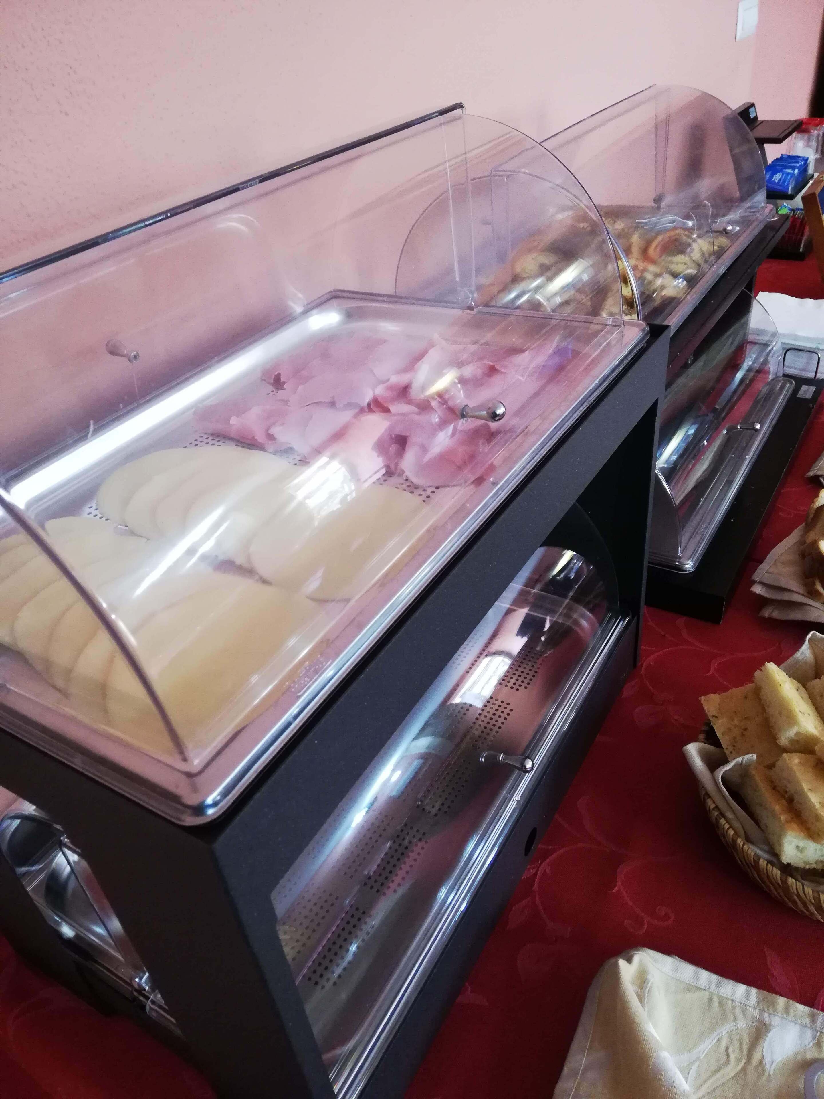Un bufé con distintos alimentos, incluyendo embutidos y pan.