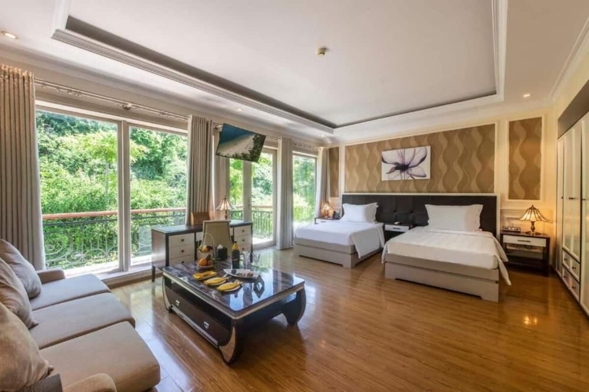 A spacious bedroom with a large bed, a smaller bed, a sofa, and a dining table.