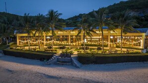 A beachfront hotel with outdoor seating and palm trees. - Hon Tam Resort (Nha Trang)