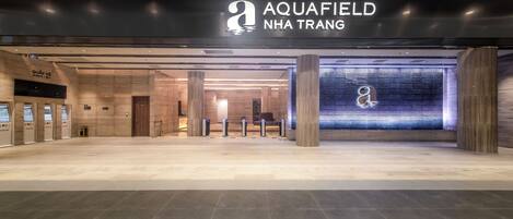 La entrada de un hotel con diseño moderno, destacando un cartel grande que dice 'Aquafield Nha Trang'.
