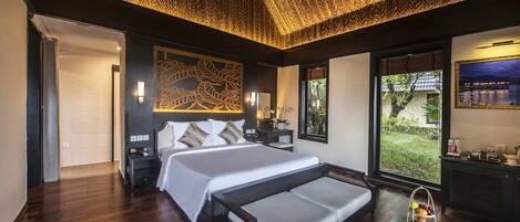 A modern bedroom with a large bed, a ceiling fan, a nightstand, and a view of the outdoors.