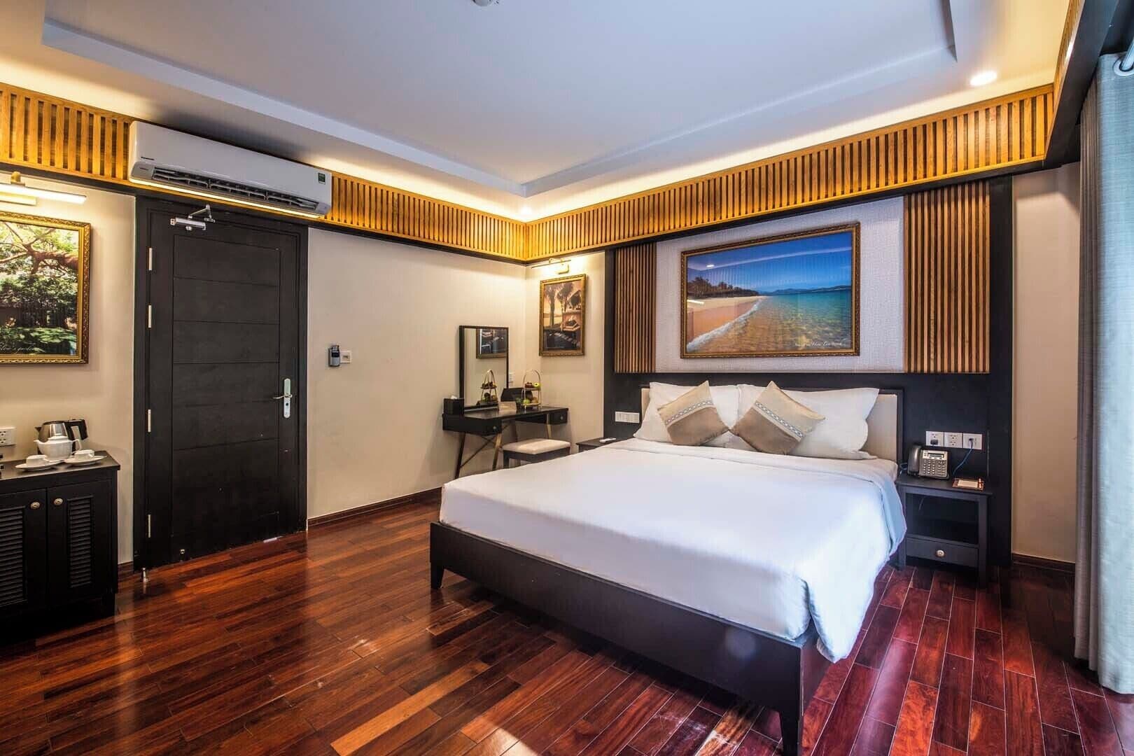 A modern hotel room with a large bed, a desk, and a wardrobe.
