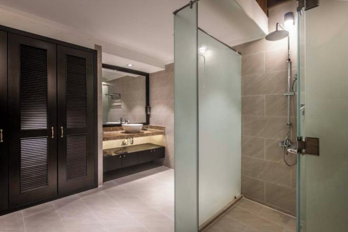 A modern bathroom with a glass-enclosed shower, a dark wooden vanity, and a large mirror.
