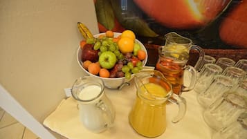 Una mesa con un cuenco de fruta, una jarra de té y una jarra de jugo.