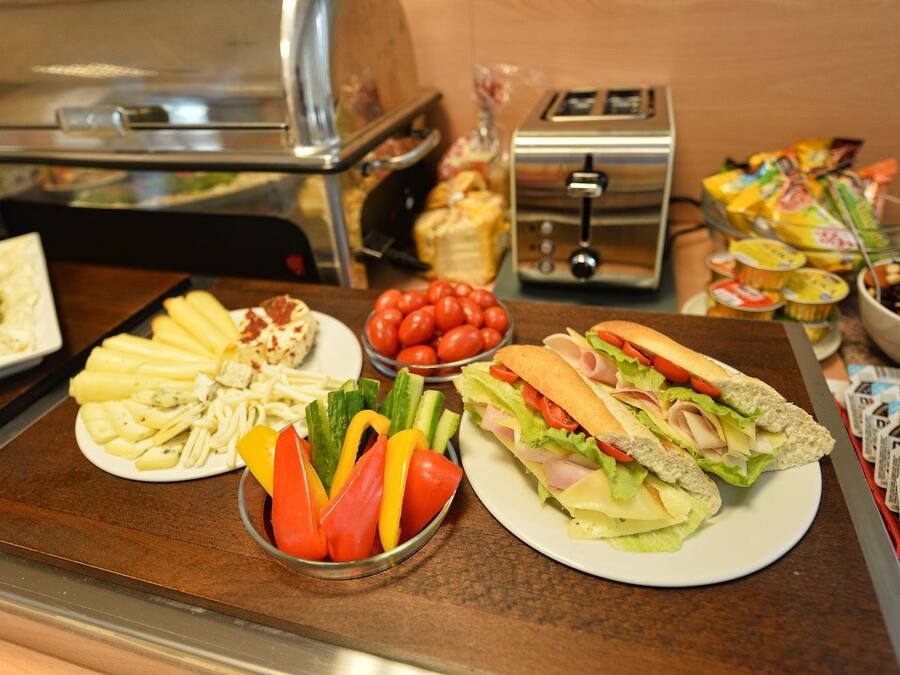 Een buffet met diverse gerechten, waaronder belegde broodjes, salades en fruit.