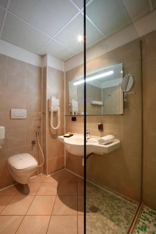 Un baño con inodoro, lavamanos y zona de ducha.