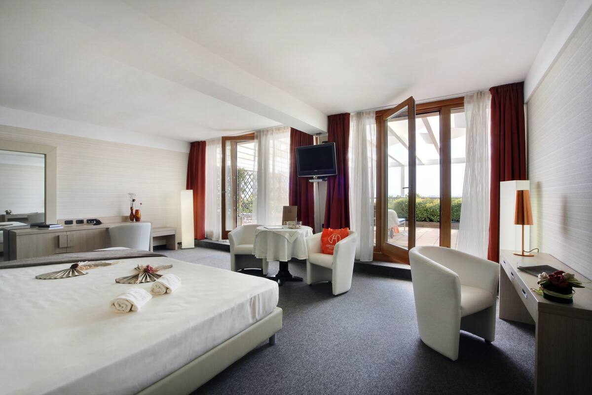 Ein Hotelzimmer mit einem großen Bett, einem Schreibtisch, einem Stuhl, einem kleinen Tisch und einem Fernseher.