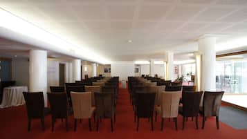 Ein Konferenzraum mit Reihen von Stühlen, einem roten Teppich und einer weißen Decke mit Rastermuster.