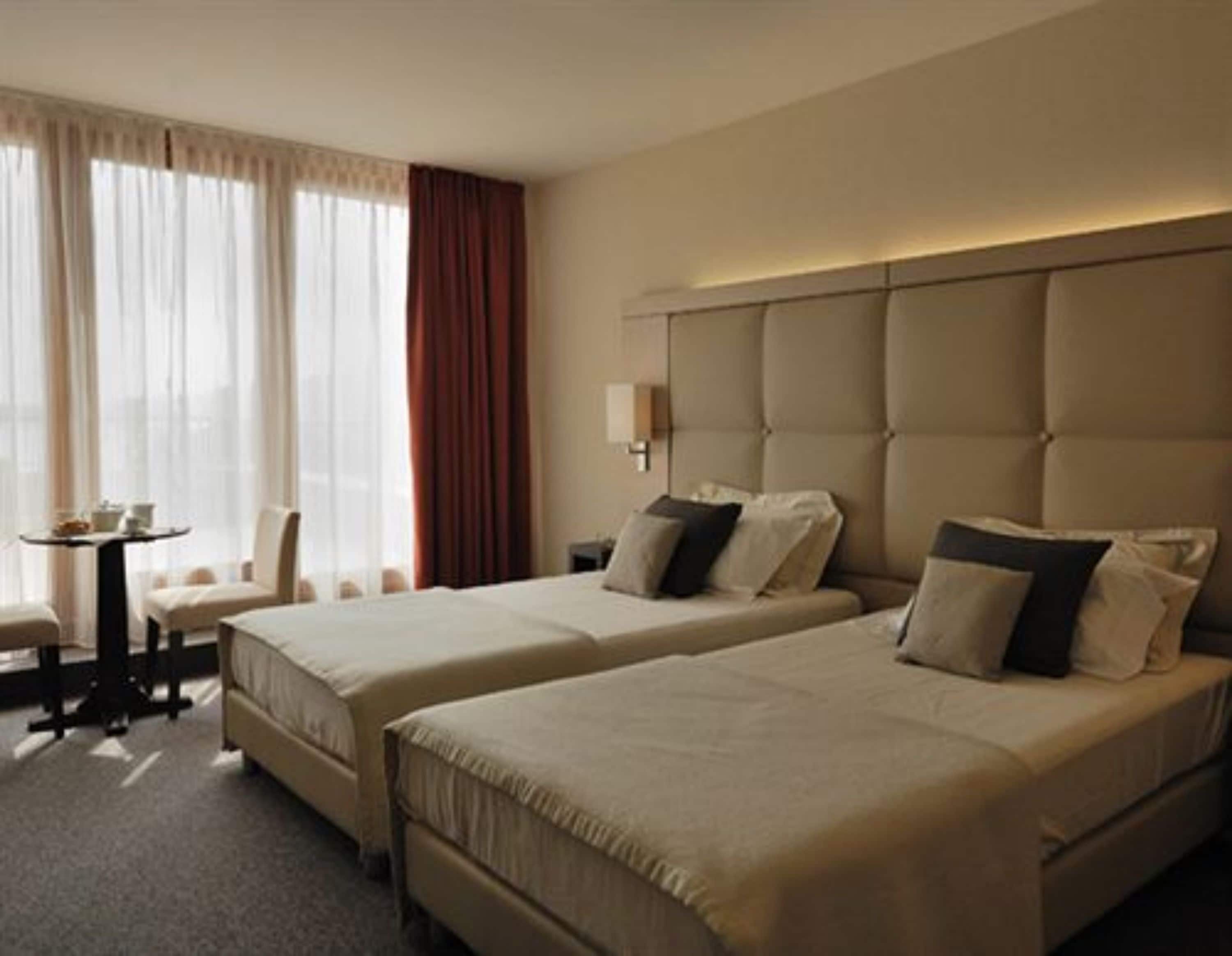 Una habitación de hotel con dos camas, una mesita y una silla.