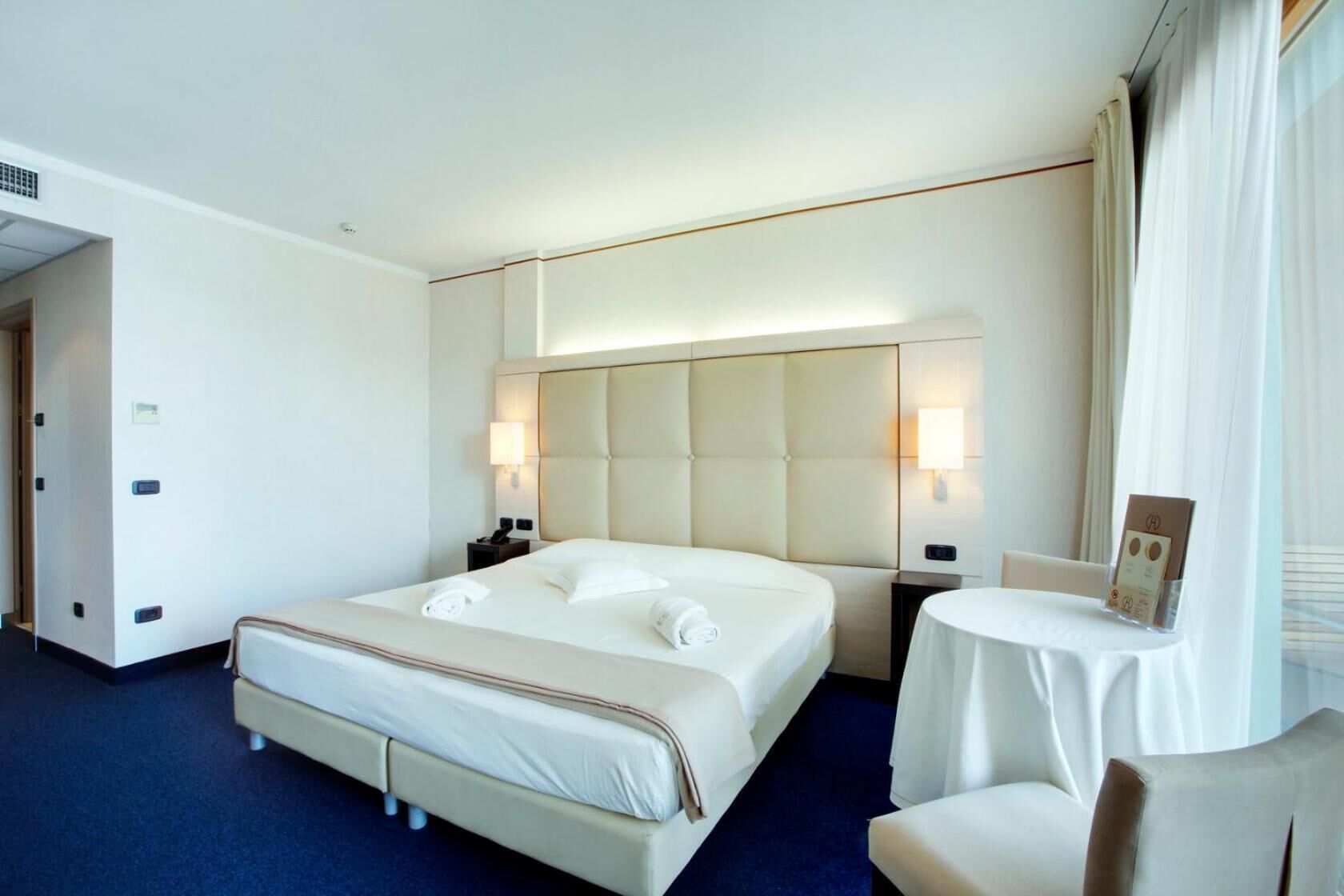Une chambre d’hôtel avec un grand lit, des tables de chevet, une chaise et une petite table.