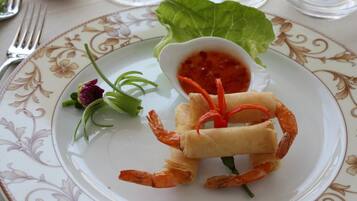Ein Teller mit einem gerollten Frühlingsrollen, Garnelen und einer kleinen Sauce.