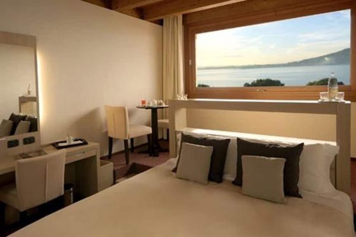 Ein Hotelzimmer mit Bett, Schreibtisch, Stuhl und einem Fenster mit Seeblick.