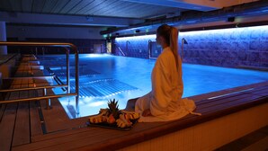 A person sitting by a poolside with a tray of fruits, in a room with tiled walls and a wooden bench. - Cocca Hotel Royal Thai SPA (Sarnico)